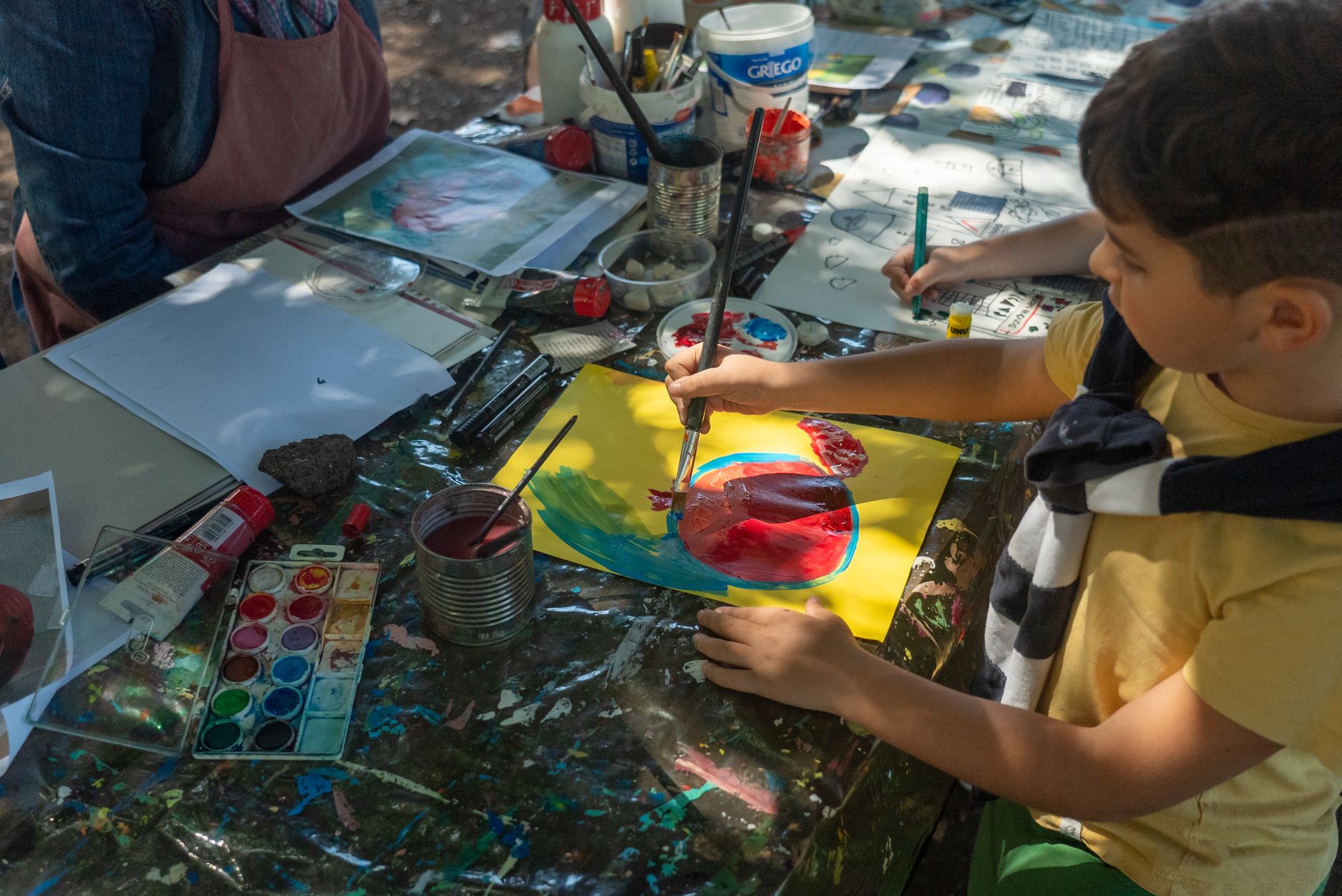 boy sitting by table and painting